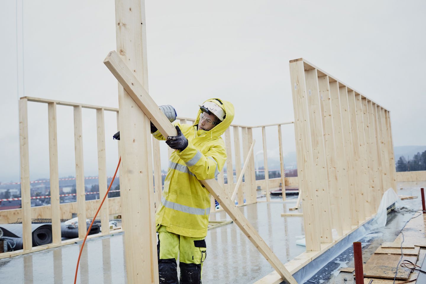 Person i arbeidstøy som setter opp reisverket til et hus. Foto.